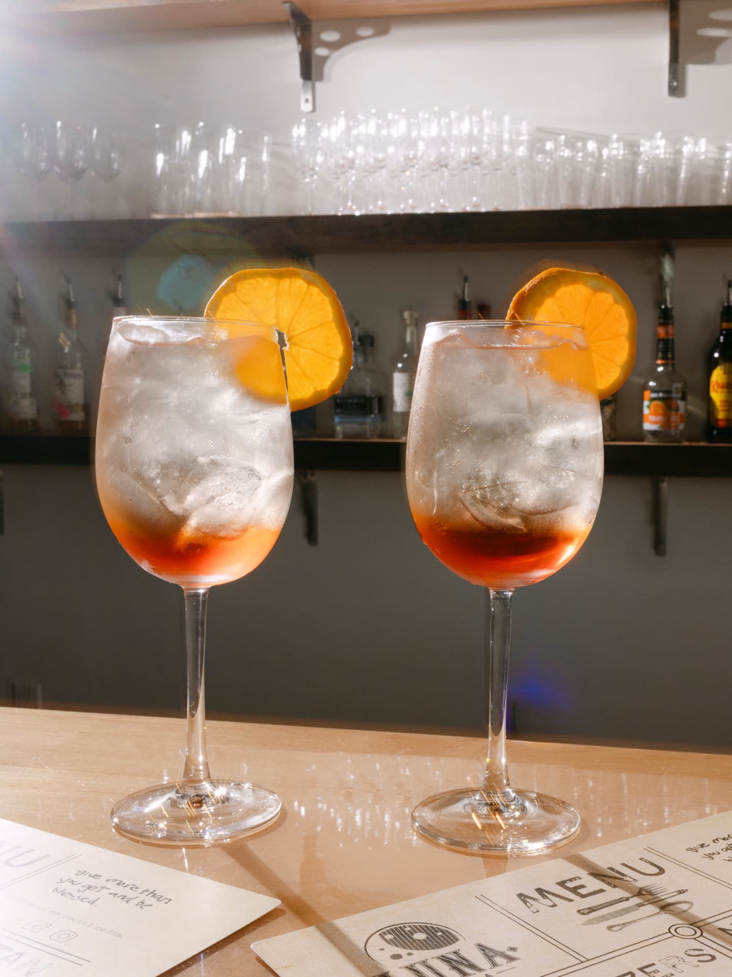 Two refreshing cocktails garnished with orange slices on the Luna bar
